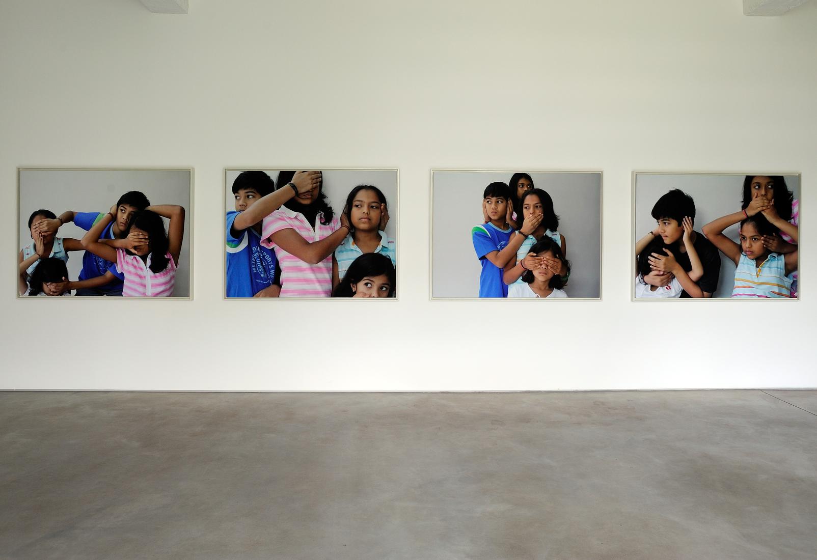 Four large photos installed on a gallery wall: fou...