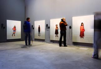People in a gallery looking at almost life size ph...