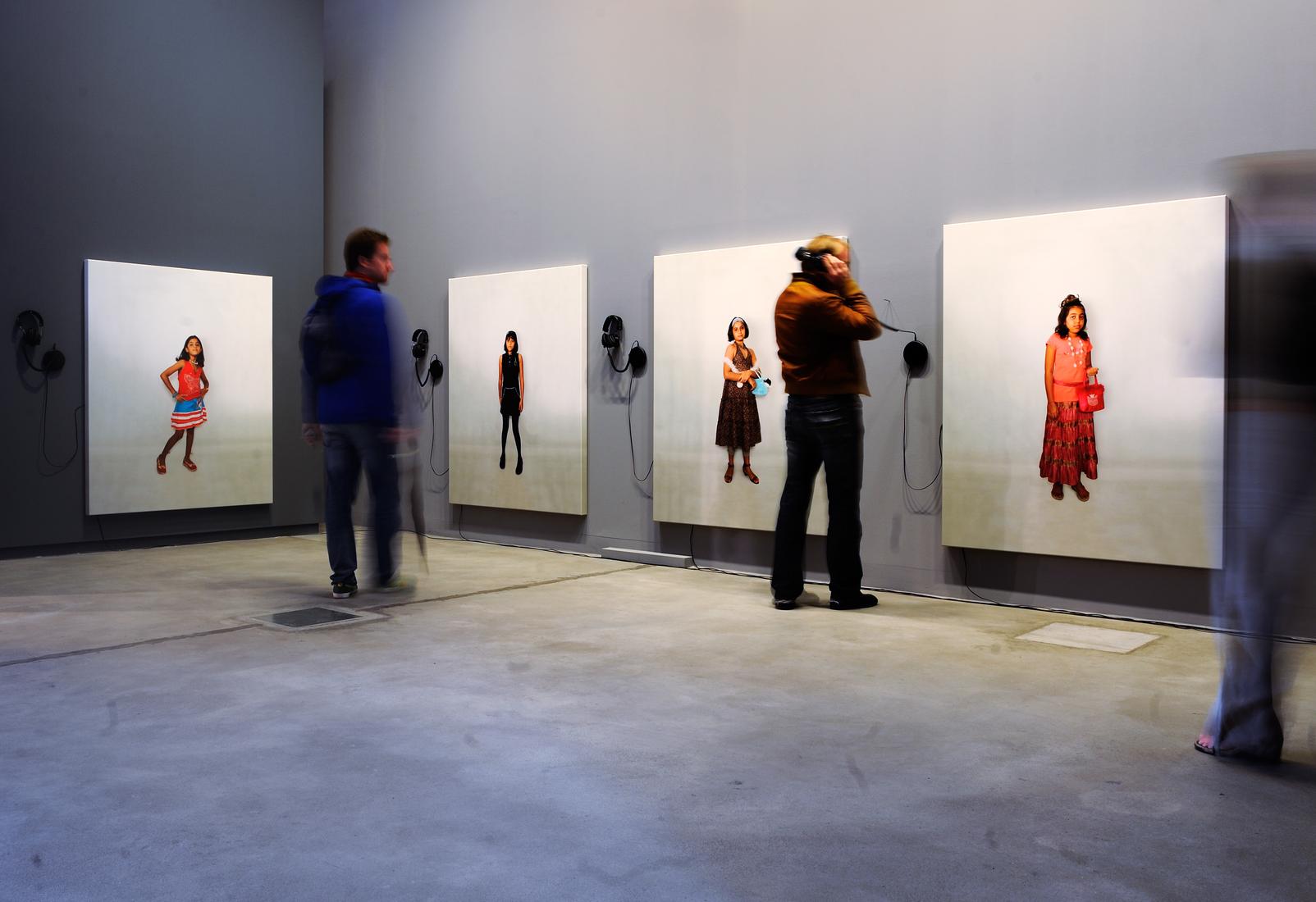 People in a gallery looking at almost life size ph...
