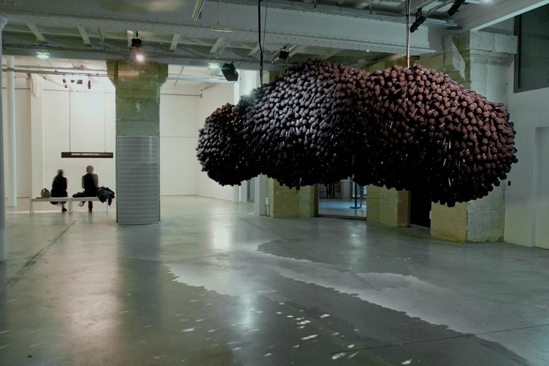 A lumpy mass of microphones hung from a gallery ce...