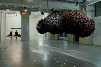 A lumpy mass of microphones hung from a gallery ce...